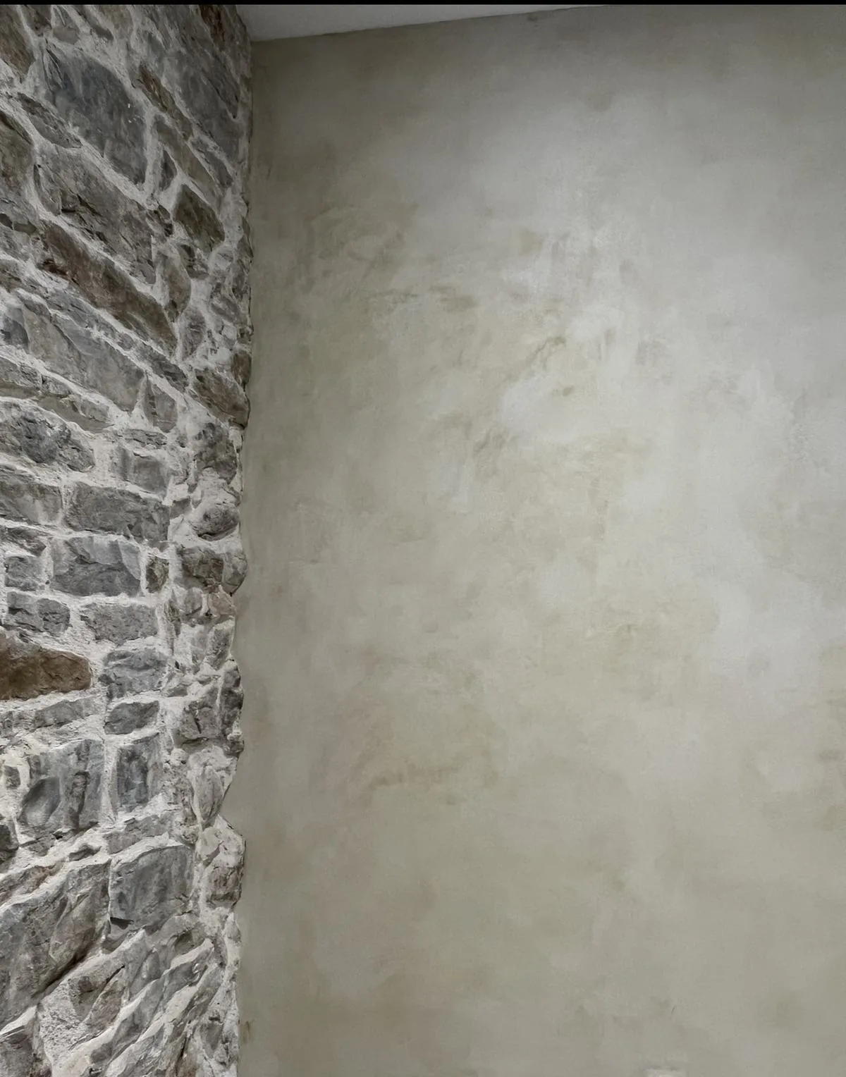 Mur en enduit à la chaux lissée à côté d'un parement de pierre apparente